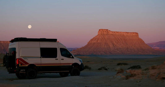 adventure van looking out at the rising moon in the desert