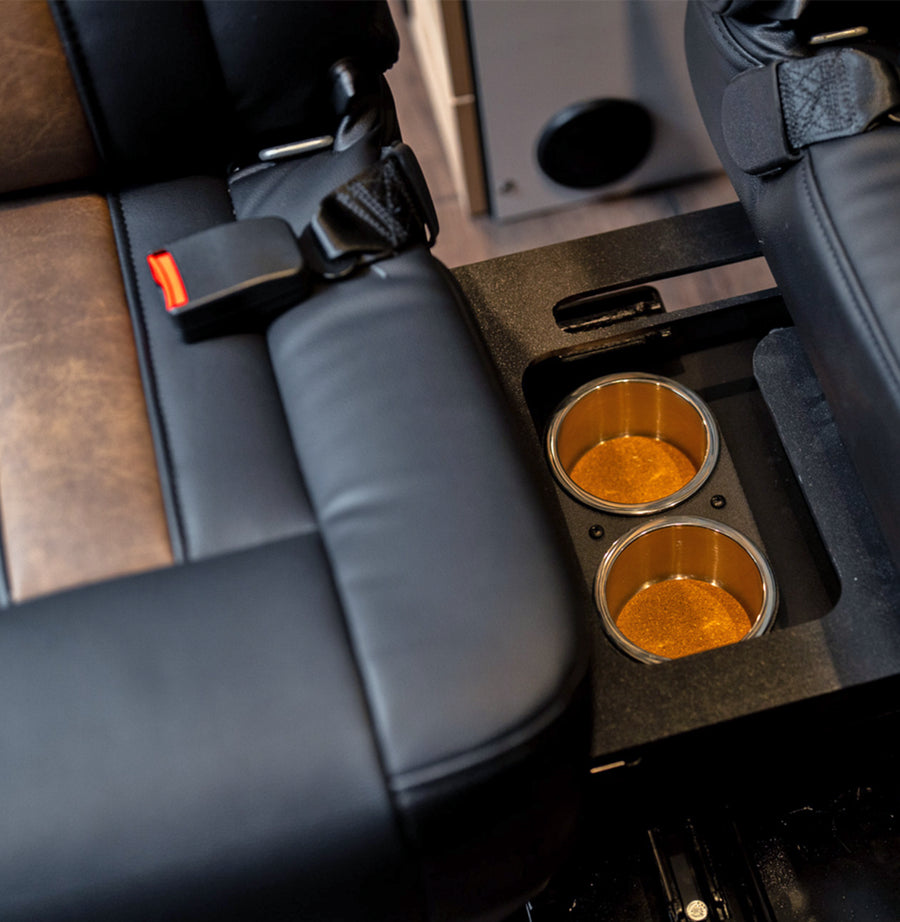 Cup holders between black leather camper van seats, ideal for adventure van or vanlife travel.