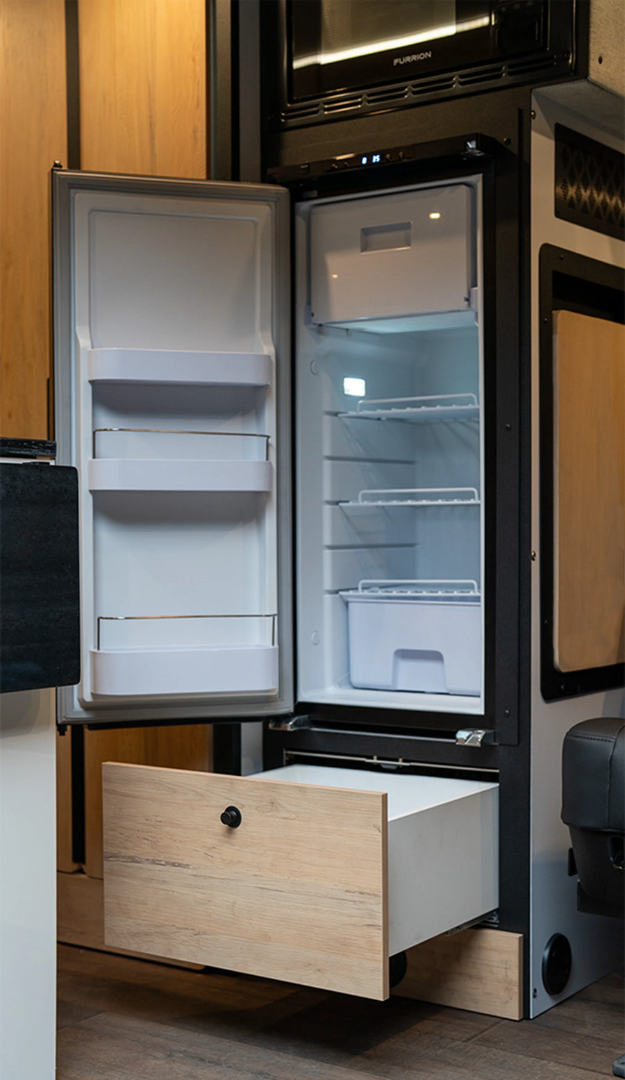 Open fridge and storage drawer inside modern camper van, custom van, Class B RV interior