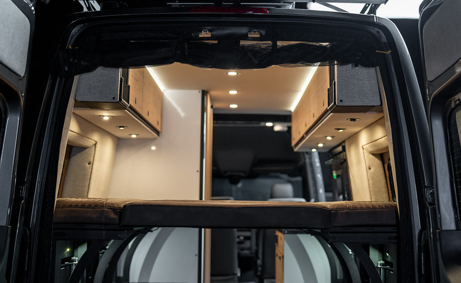 Modern camper van interior trunk view with storage, lighting, and bed setup for vanlife adventure travel
