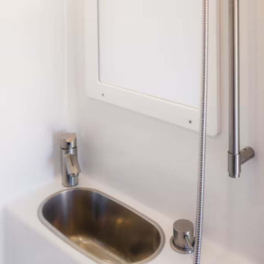 Compact stainless steel bath sink with modern faucet in adventure van camper bathroom