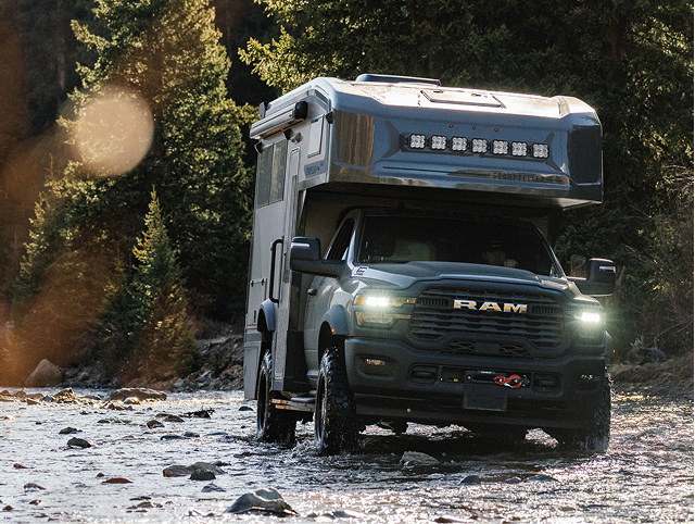 GXV Wild RAM truck with a camper shell driving on a rocky river trail