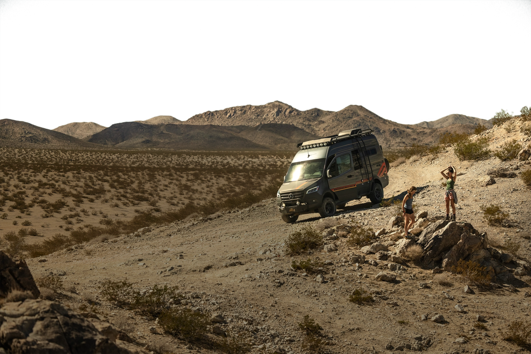 Overlanding 4x4 van on desert trail with adventure travelers, perfect for vanlife and off-road expeditions.