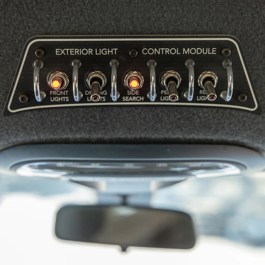 Exterior light control module in a Storyteller MODE 4x4 adventure van, featuring toggles for front, driving, side search, and rear lights.
